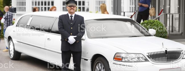 A proud chauffeur standing beside a white stretch limousine